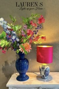 Kleurrijke zijden bloemen in vaas met een tafellamp erbij.