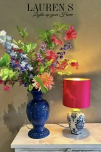 kleurrijke foto van een blauwe vaas met lentebloemen erin en ernaast een Delftsblauwe lampenvoet met knalroze zijden lampenkap