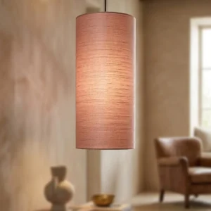 zand beige interieur. op de voorgrond hangt een smalle hoge lampenkap in oud roze zijde. het licht schijnt er zacht doorheen.